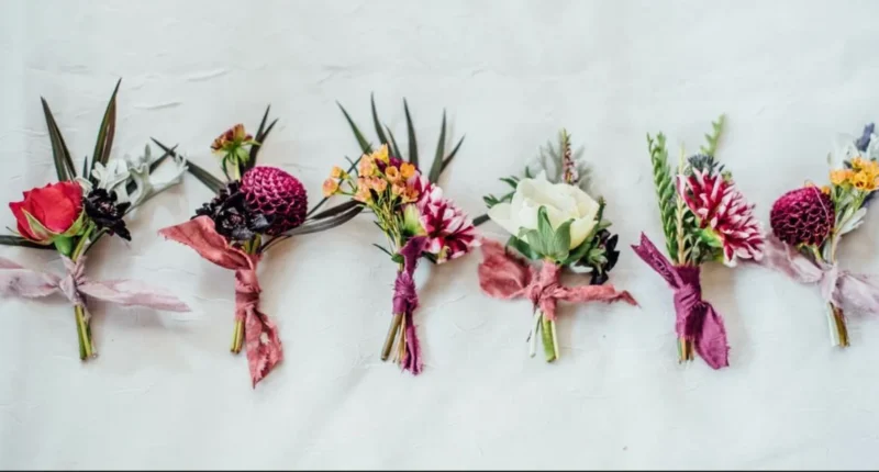 A flat lay of various trendy boutonnières in different colors and styles displayed on a white background