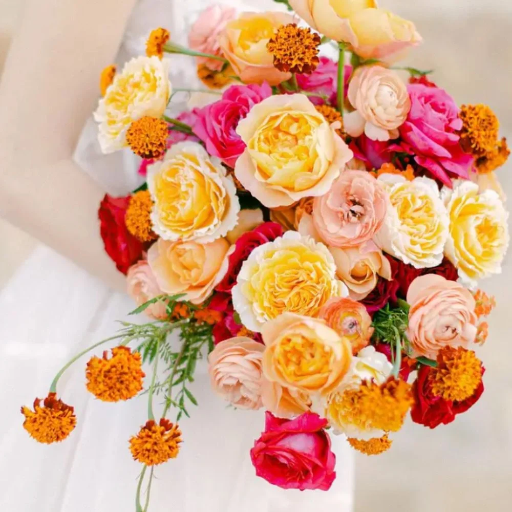 Close-up of colorful boutonnières with red roses, orange ranunculus, blue anemones, and purple orchids arranged on velvet