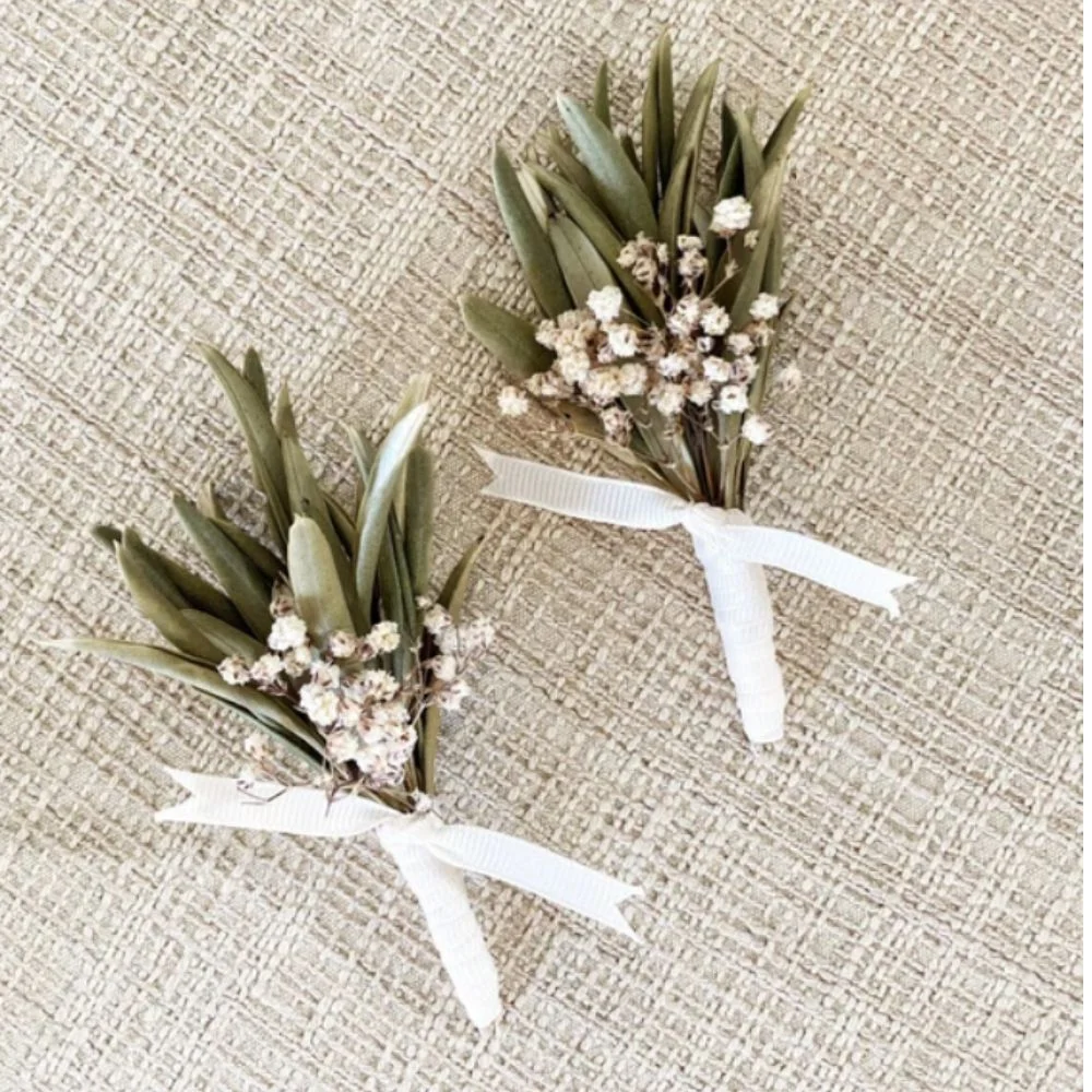 Fresh green boutonnière crafted from rosemary, olive leaves, and ferns on a linen fabric background