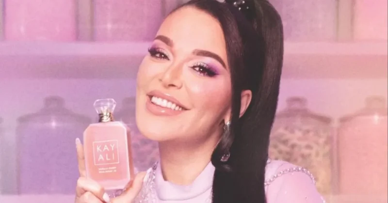 Mona Kattan holding a luxurious Kayali perfume bottle at the brand’s floral-themed launch event.