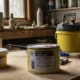 Two containers labeled "Paint Thinner" and "Mineral Spirits" placed on a workbench alongside paintbrushes, gloves, a paint can, and safety gear in a well-ventilated workspace.