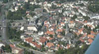 Aerial view of Hattingen showing old town rooftops, the Ruhr River, castle ruins, and surrounding green hills in warm sunset light