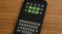 A smartphone screen showing a Wordle game with letter guesses highlighted.