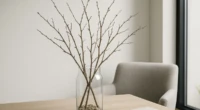 A glass vase with Scandinavian twigs on a wooden table in a minimalist interior.