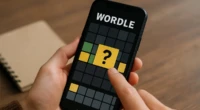 A person playing Wordle on a smartphone with colored tiles.